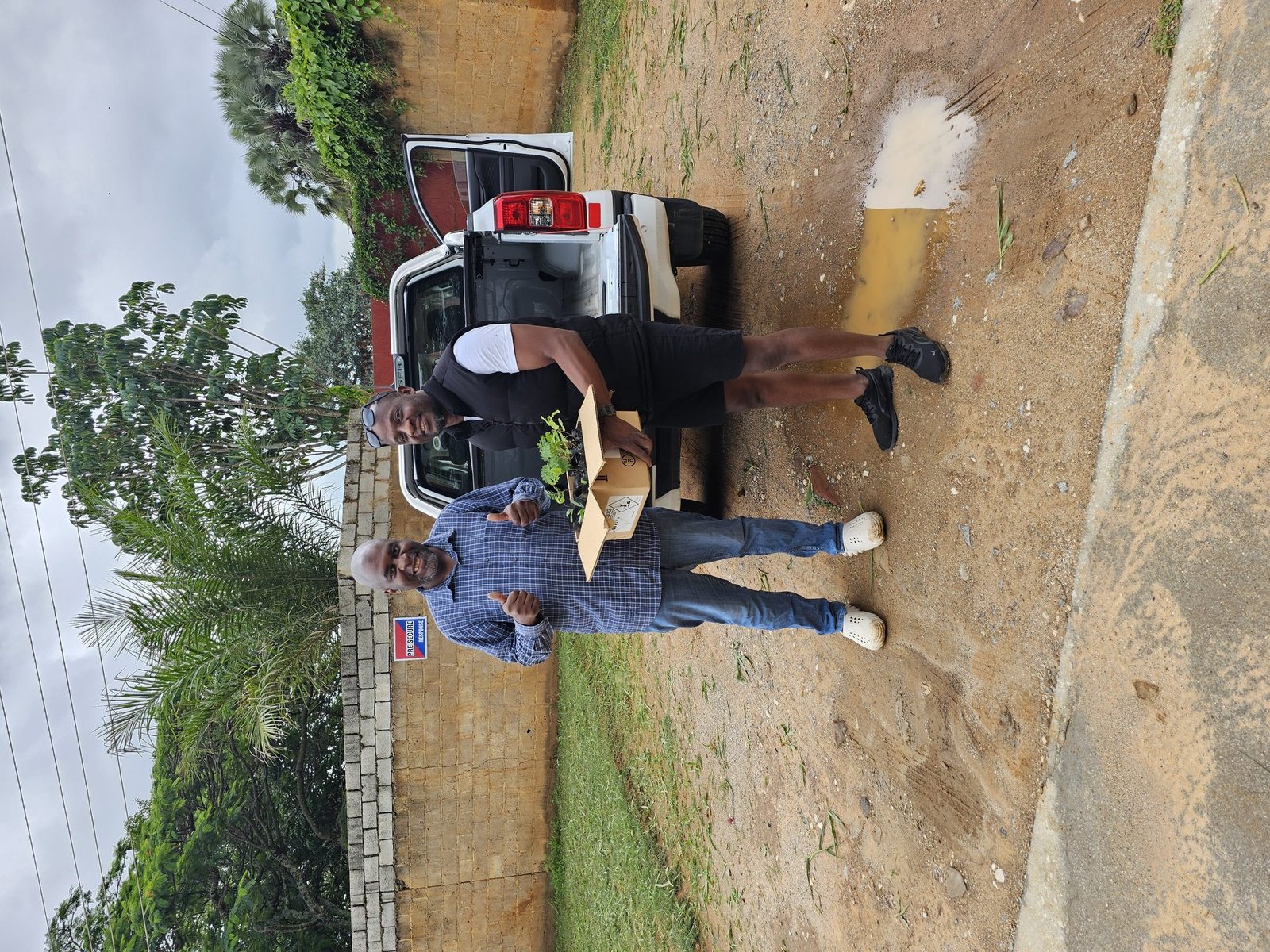 Two men with thumbs up — seedlings collected